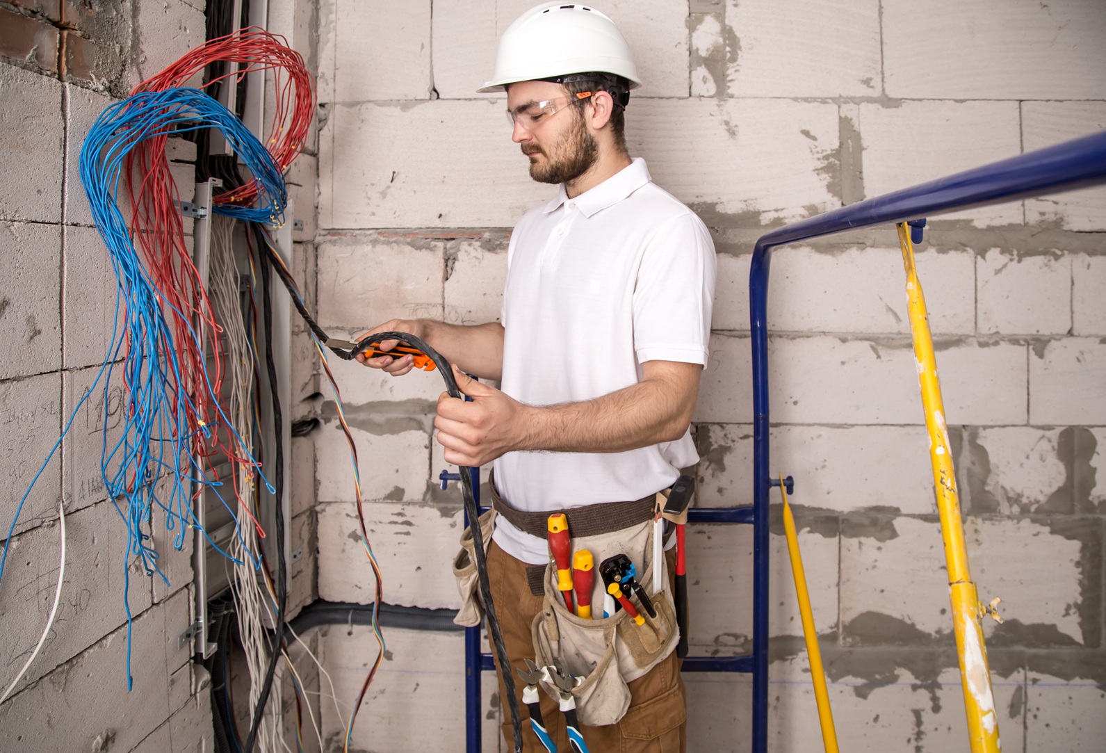Electrician working near the Board with wires. Installation and connection of electrics. Professional with tools in hand.
